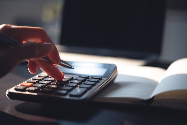 Close up, business woman working at office, using calculator to calculate company finance, accounting with laptop computer on table, budget management. Doing finance, budgeting and tax calculation