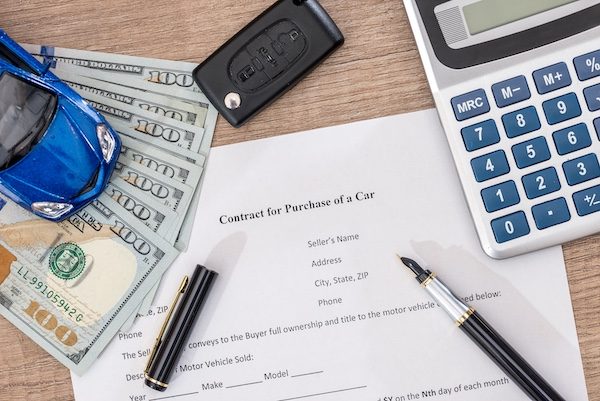 documant, dollar, pen, calculator and toy car with keys.